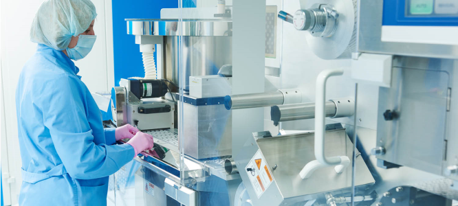 Pharmacy worker in protective gear safely operates machinery